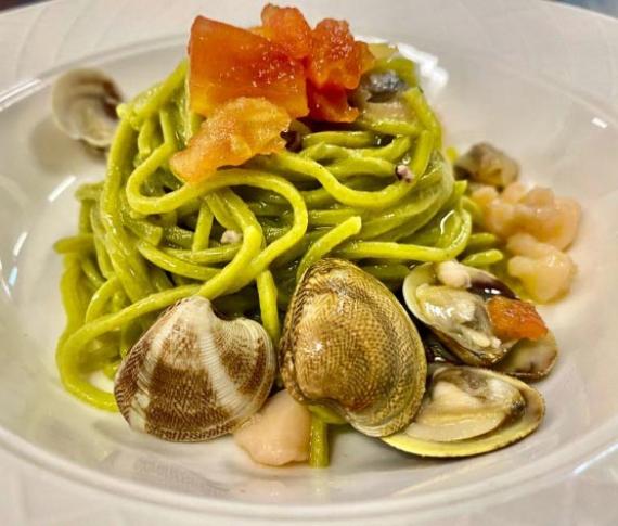 Spaghetti verdi con vongole e pomodori freschi.