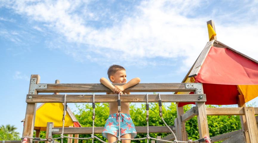 Bambino su torre di legno in parco giochi soleggiato.