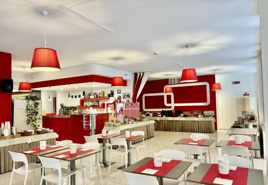 Ristorante moderno con arredamento rosso e bianco, atmosfera accogliente.