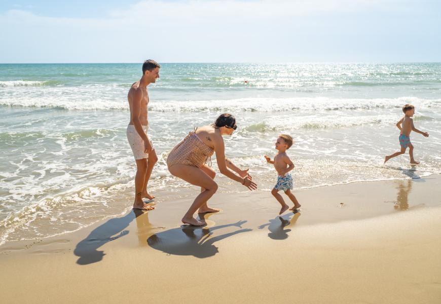 Famiglia gioca sulla spiaggia in una giornata di sole.