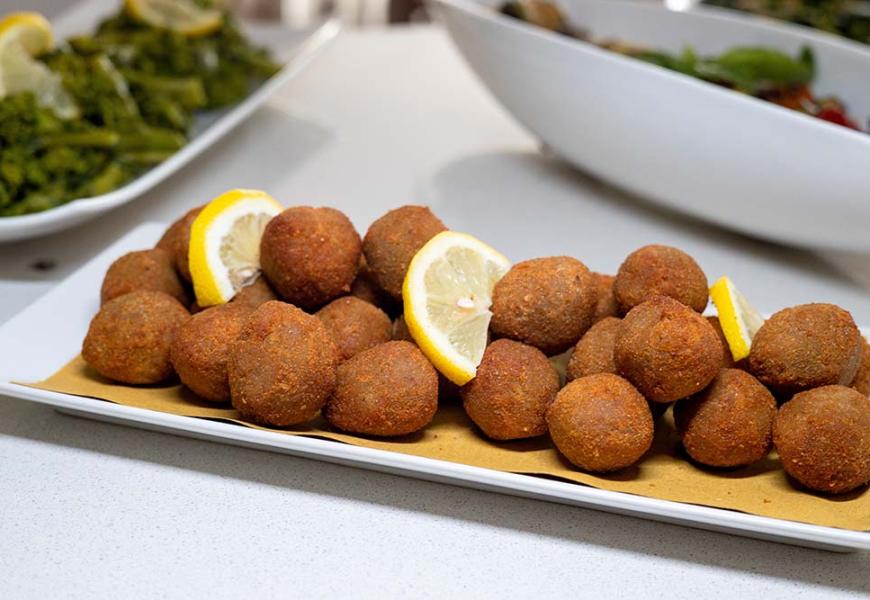 Polpette fritte servite con fette di limone su un piatto.