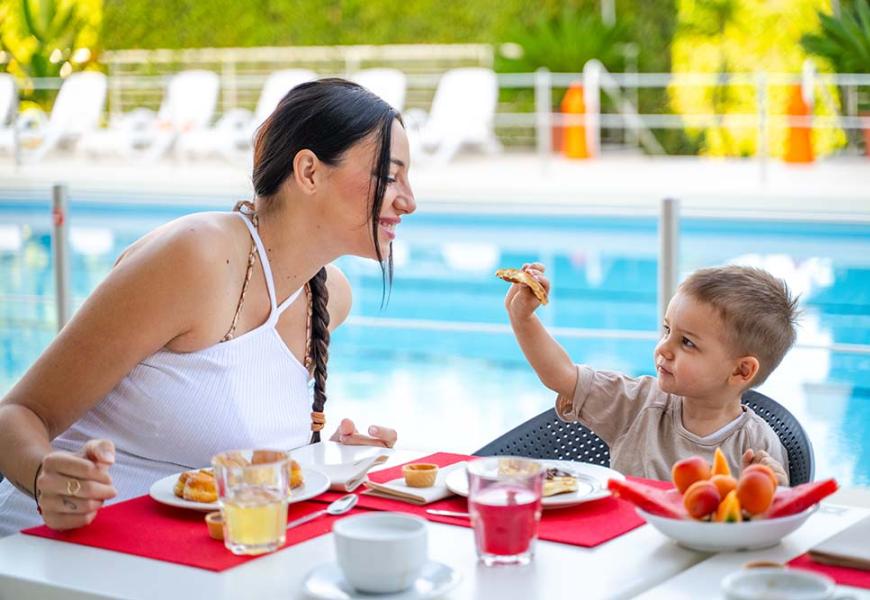 Colazione all'aperto vicino alla piscina con madre e figlio.