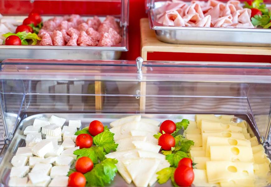 Buffet con formaggi, affettati, pomodorini e verdure.