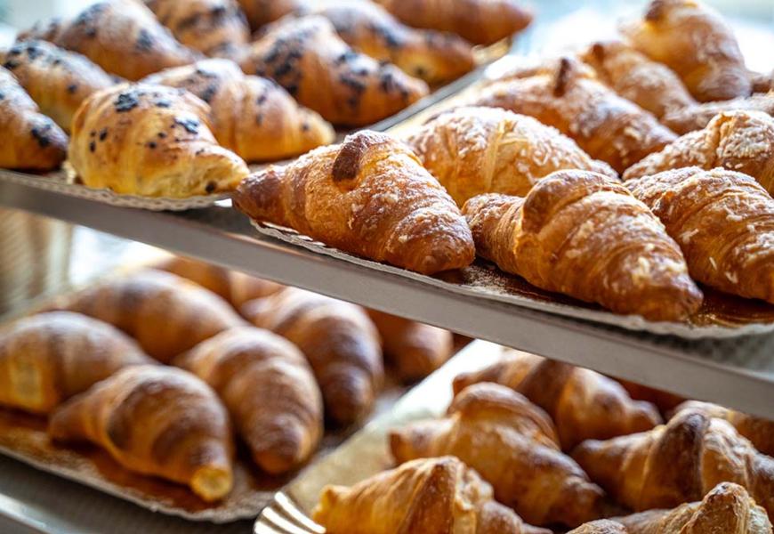 Croissant freschi su vassoi in una panetteria.