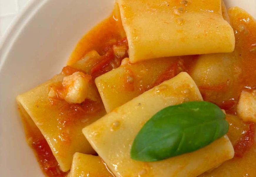 Paccheri con pomodoro e basilico, serviti in un piatto bianco.