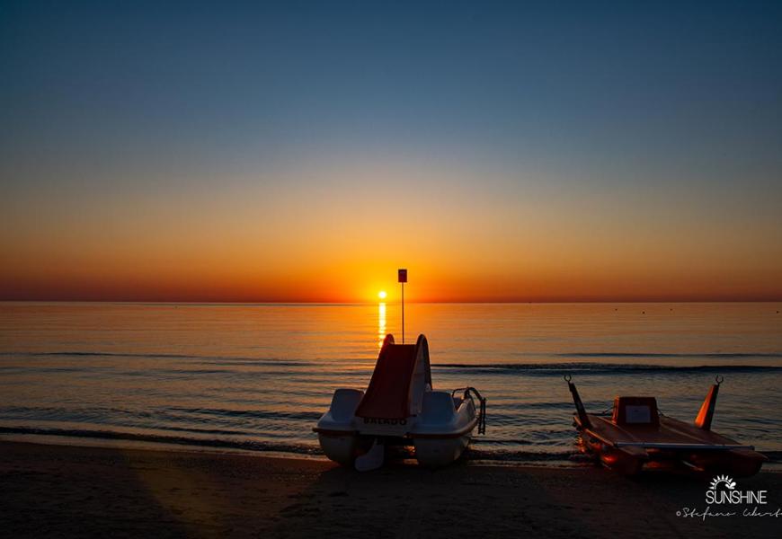 Tramonto sul mare con pedalò sulla spiaggia.