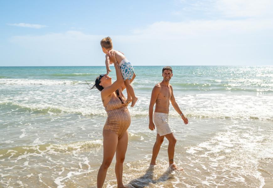 Famiglia felice sulla spiaggia con il mare sullo sfondo.