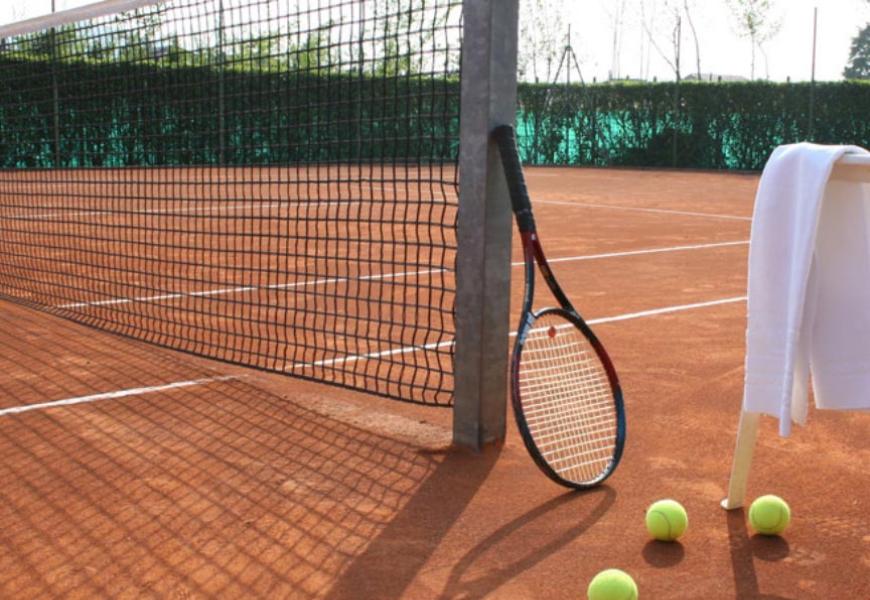 Campo da tennis in terra rossa con racchetta e palline.