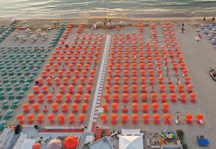 Spiaggia con ombrelloni colorati allineati in file ordinate.