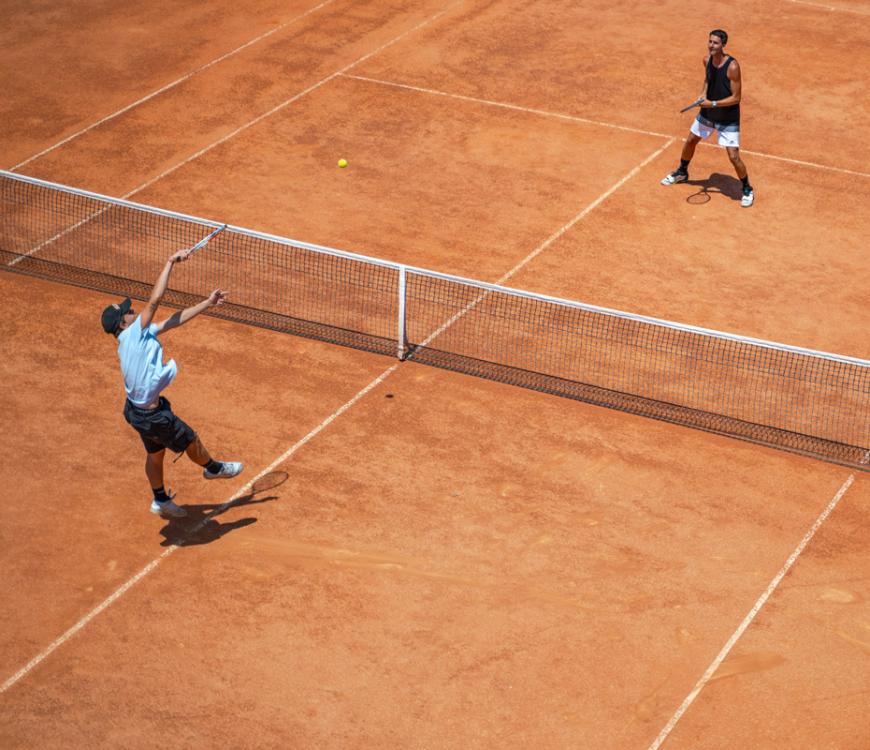 Due giocatori di tennis su un campo in terra rossa.